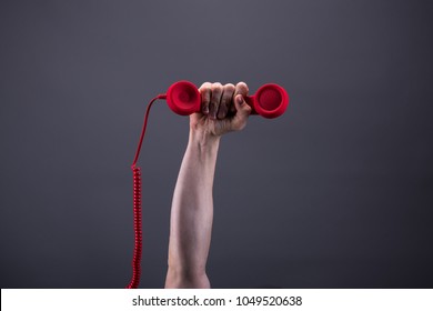 Strong Arm And Hand Holds A Red Telephone Up In The Air