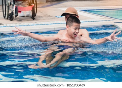 Strong Arm Muscles Of Asian Special Child On Wheelchair With Swimming Pool Background,The Boy Happiness In Holidays With Family Time On The Travel,Lifestyle Of Happy Disabled Kid Sport Travel Concept.