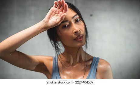 Strong Asian Female Wipes Sweat From Forehead, Looks At Camera. Concept Of Successful Empowered Woman Fighting And Winning Fight Against Injustices, Prejudices. Cinematic Stylish Portrait