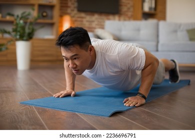 Strong asian mature man making strength workout, doing push ups on sports mat, having domestic workout. Sporty korean male training his body, leading active lifestyle - Shutterstock ID 2236696791