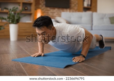 Strong asian mature man making strength workout, doing push ups on sports mat, having domestic workout. Sporty korean male training his body, leading active lifestyle Foto stock © 