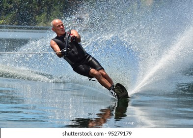 A strong athletic active senior man water skier in his 70's preforming water skiing sport skills on lake in New Zealand. Healthy lifestyle  concept. Real People. Copy space 