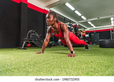 strong athletic black woman in a gym doing push-up exercises in red sportswear - Powered by Shutterstock