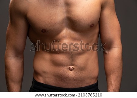 Strong athletic man. Close up view of the fitness model showing his perfect abs isolated on black background with copy space 