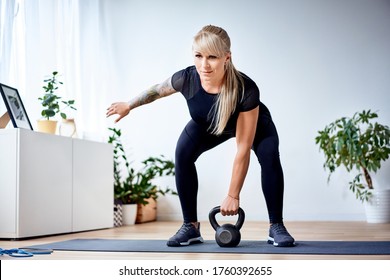 Strong athletic woman doing home workout with kettlebell weight - Powered by Shutterstock