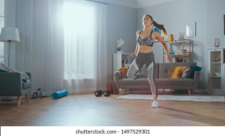 Strong and Beautiful Athletic Fitness Girl in Sportswear is Doing Cardio Exercises in Her Sunny and Spacious Living Room with Minimalistic Interior.