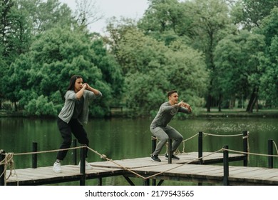 Strong and beautiful couple working out and trying to jump on the bridge near the lake in the park