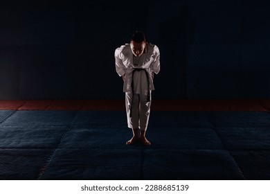 Strong and beautiful karate girl bowing at the karate studio while standing - Powered by Shutterstock