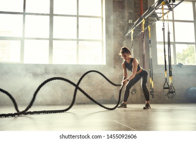 Strong and beautiful. Young athletic woman with perfect body doing crossfit exercises with a rope in the gym. - Powered by Shutterstock