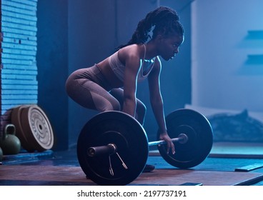 Strong, black woman and focus barbell fitness to deadlift workout, heavy exercise and dark gym training. Powerful athlete, bodybuilder muscles and motivation challenge for sports squat weightlifting - Powered by Shutterstock