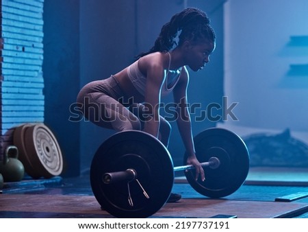 Strong, black woman and focus barbell fitness to deadlift workout, heavy exercise and dark gym training. Powerful athlete, bodybuilder muscles and motivation challenge for sports squat weightlifting