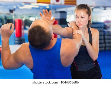 Strong Bold  Cheerful  Woman Is Training With Man On The Self-defense Course In Gym.