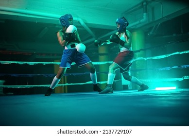 Strong boxer girls training sparring before competition. Two young girls in helmets and gloves actively boxing, demonstrating punches and skills to trainer. Healthy lifestyle and extreme sport concept - Powered by Shutterstock