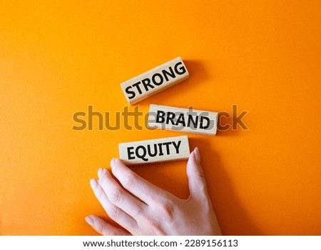 Strong Brand Equity symbol. Concept words Strong Brand Equity on wooden blocks. Businessman hand. Beautiful orange background. Business and Strong Brand Equity concept. Copy space