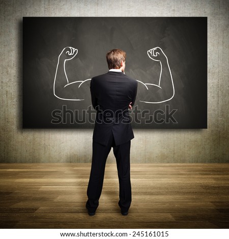 strong businessman standing in front of a chalkboard
