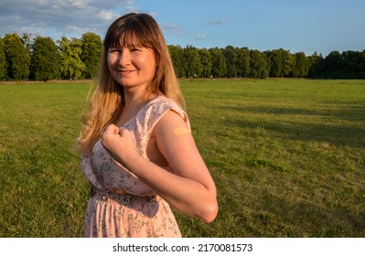 Strong Cheerful Vaccinated Woman Flexing Arm Muscle Showing With Adhesive Bandage After Vaccine Injection For Covid-19. Stay Strong And Protected During A Pandemic