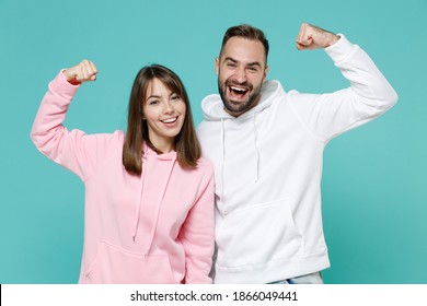 Strong cheerful young couple two friends man woman 20s wearing white pink casual hoodie standing showing biceps muscles looking camera isolated on blue turquoise colour background studio portrait - Shutterstock ID 1866049441