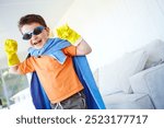 Strong, child and happy superhero in home to play fantasy game on halloween. Smile, cute boy and hero with power in costume to fight for justice, laugh or flex muscle for creative cosplay in lounge