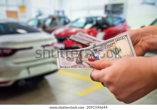 strong clean healthy hands\
firmly hold a round sum of dollar banknotes on the background of\
the car in the car. Car interior concept. The concept of buying and\
selling.