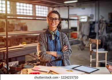 Strong confident middle aged woman engineer standing and looking at the camera at her workshop. - Powered by Shutterstock