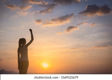 Strong confident young woman with her fist up in the air.