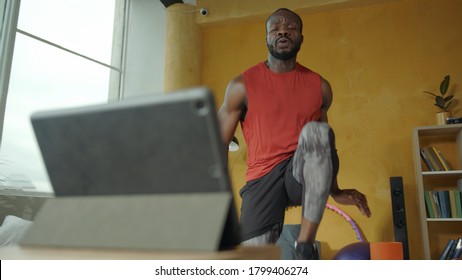 Strong Cross Fit Afro-american Man Doing Leg Crunches Exercises With Online Trainer Classes On Laptop. Workout. Home Isolation. Sports, Healthy Lifestyle Concept.