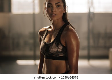 Strong and determined female in sportswear standing in the gym and looking at camera. Sportswoman after intense crossing training workout session in gym. - Powered by Shutterstock