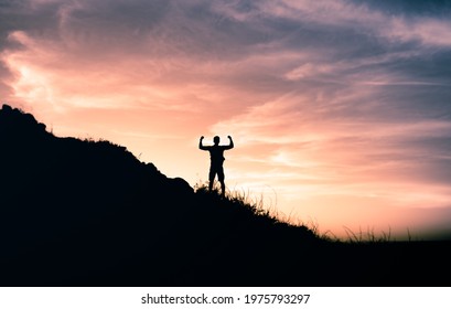 Strong Determined Man On Mountain Top Flexing Facing The Sunrise. Adventure, Determination And Will Power Concept. 