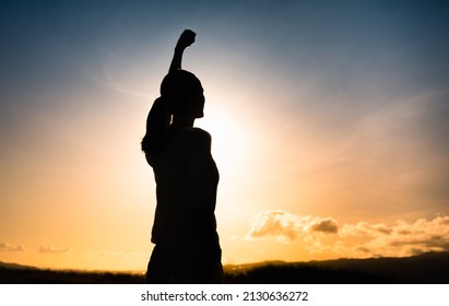 Strong, determined young woman facing the sunset or sunrise. Never give up, people power, inner strength concept.