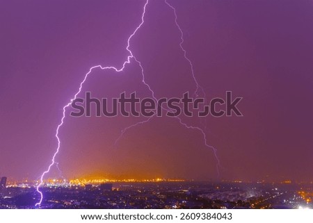 Strong electrical storm with a multitude of lightning strikes house over city lights night