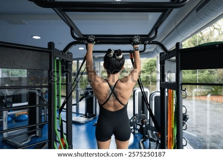 Similar – Image, Stock Photo Determined woman performing pull-up exercise at gym