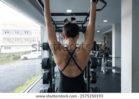 Similar – Image, Stock Photo Determined woman performing pull-up exercise at gym