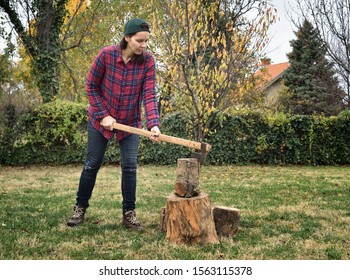 Strong female lumberjack chopping wood with an axe in the backyard - Powered by Shutterstock