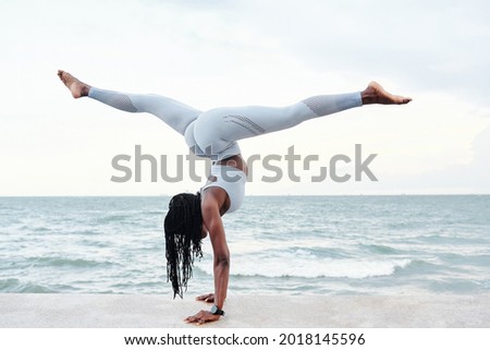 Strong fit young woman doing handstand splits on sandy beach