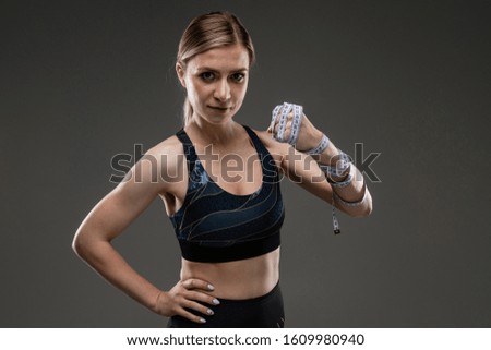 Similar – Close up front portrait of one young athletic woman in sportswear in gym over dark background, standing in boxing stance with hands and fists, looking at camera