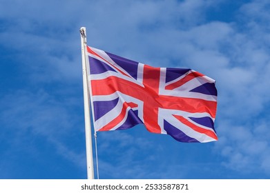 A strong gust of wind captures the Union Jack as it waves gracefully against a clear blue sky, symbolizing unity and pride in British culture on a bright day. - Powered by Shutterstock