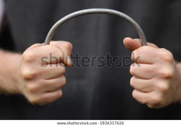 Strong hands bend a metal\
rod