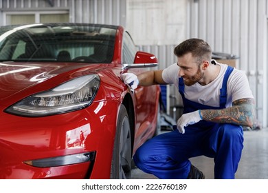 Strong happy smiling young male professional technician car mechanic man 20s wears denim blue overalls white t-shirt gloves check car painting work in light modern vehicle repair shop workshop indoor - Powered by Shutterstock