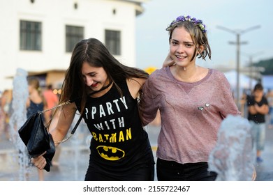 Strong heat in the city: laughing girls playing with fountain water jets at the square. June 5, 2018. Kyiv, Ukraine