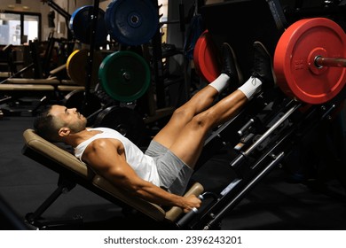 Strong Hispanic man doing leg press at a gym.