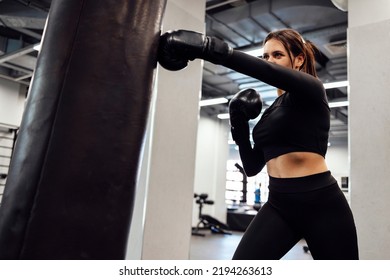 Strong latin boxing woman jump kick to huge punching bag at fitness gym. Athletic girl training Muay Thai boxing for bodybuilding and healthy lifestyle concept. Workout in sport club - Powered by Shutterstock