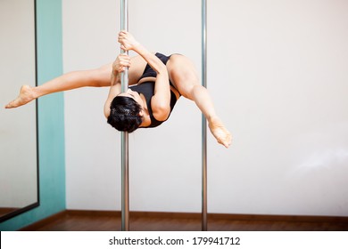 Strong Latin Woman Holding A Pose During A Pole Dancing Class At A Gym