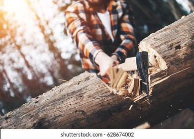 Strong logger in a plaid shirt chopping a big tree. Wood chips fly apart - Powered by Shutterstock