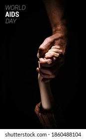 Strong Male Hand Hold Child Hand On A Black Isolated Background. First December World AIDS Day Cancer Control Concept Symbolizing Day Of AIDS And HIV. Support And Care Concept Vertical Image