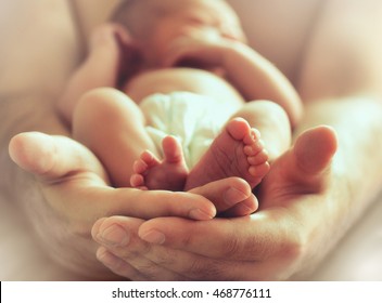 Strong Male Hands Holding Sleeping Newborn Baby, Photo With Soft Blur Effect