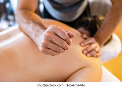 A strong male massage therapist giving a man a deep tissue massage. Physical therapy and chiropractic treatment concepts