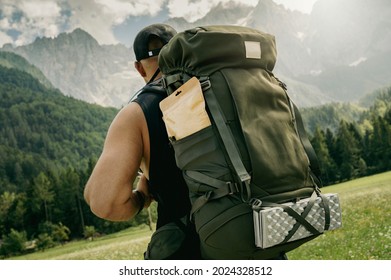 Strong Man with big backpack going on a hike, Alpine mountains in background