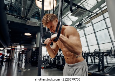 Strong man doing exercise on to gymnastic rings at gym. Fit male athlete training on gymnastic rings in light sport hall - Powered by Shutterstock