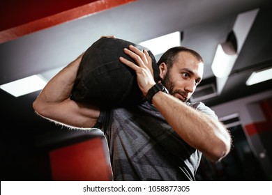 Strong Man Doing Training With Sandbag At The Gym.