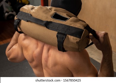 Strong Man Doing Training With Sandbag At The Gym.